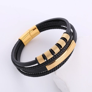Detail of men's multi-layer woven black leather bracelet with gold magnetic clasp on stone