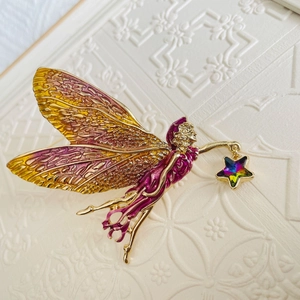 Detailed close-up of golden fairy brooch with gradient purple wings and a star charm