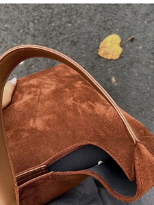 Close-up of deep brown matte suede texture on large tote bag with autumn leaf background