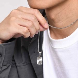 Macro view of silver stainless steel rectangular pendant with radial texture on a male neck
