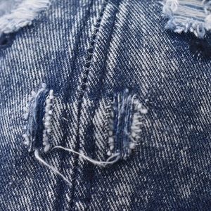 Macro shot of distressed blue denim fabric with vintage ripped holes and texture detail