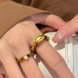 Macro shot of tiger eye beaded ring with golden lucky cat and coin charms
