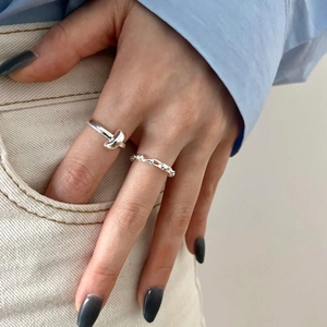 Minimalist S925 sterling silver knot and twisted rope rings worn on a model's hand