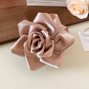 Détail d'une pince à cheveux rose en satin champagne avec texture soie sur bois