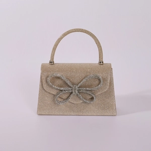Detailed macro of champagne gold evening bag with sparkling rhinestone bow embellishment