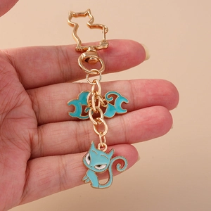 Close-up of golden cat-shaped keychain with blue enamel feline and cloud pendants