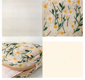 Detail view of daisy embroidery on canvas cosmetic bag with premium stitching and zipper