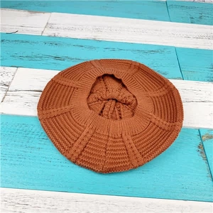 Detailed top view of a cable knit beret in rust red featuring radial textured patterns