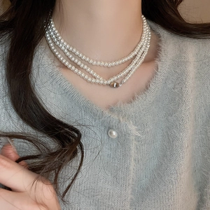 Elegante mehrlagige Perlenkette im Vintage-Stil mit Silberverschluss auf grünem Pullover