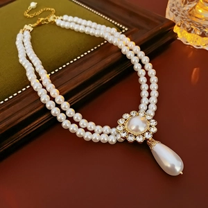 Detail of a double-layered pearl necklace with a floral rhinestone pendant on a vintage box
