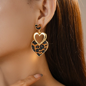 Close-up of triple heart leopard print drop earrings with gold metal accents