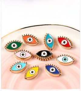 Macro detail of colorful enamel Evil Eye charms for DIY jewelry making in a ceramic dish