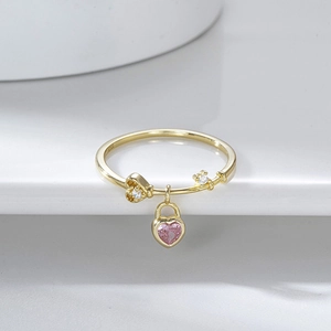 Macro detail of gold ring with pink heart lock pendant and inlaid small diamonds