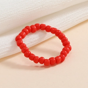 Dettaglio dell'anello elastico con perline rosse su sfondo in tessuto testurizzato bianco