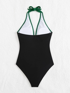 Detailed look at halter neck swimsuit with green bow tie and contrast piping details