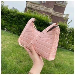 Detailed view of pink crocodile pattern leather bag with golden metallic zipper