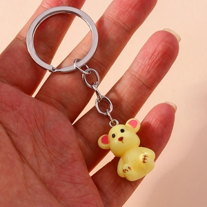 Close-up of a cute yellow bear keychain with pink ears and silver metal ring accessory