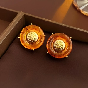 Macro shot of amber resin earrings with intricate gold daisy metal inlay details