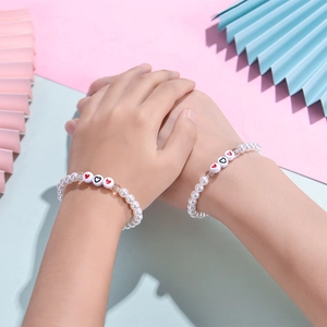 Bracelets en perles faits main avec cœurs rouges et noirs sur fond pastel coloré