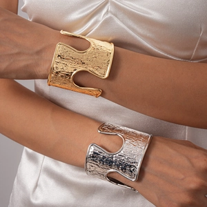 Close-up of gold and silver chunky textured cuffs on model with champagne silk fabric