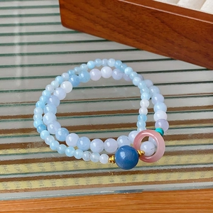 Detail of double-layer beaded bracelet with blue crystals and pink peace buckle charm