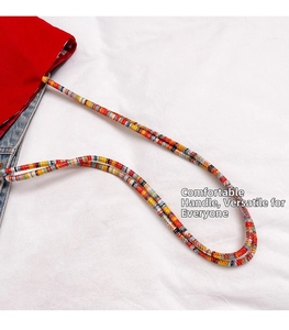 Detalle del bolso tote de lona roja con correa tejida multicolor y textura de tela