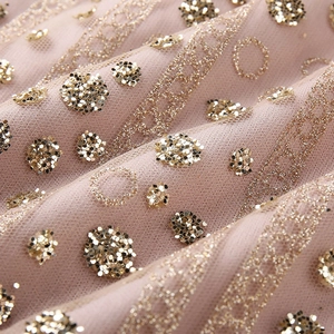 Detailed close-up of pink tulle fabric with sparkling gold sequins and polka dots
