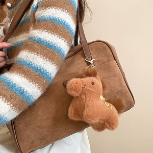Primo piano di un simpatico portachiavi a forma di cavallo di peluche marrone su una borsa