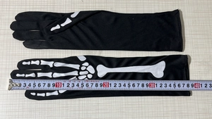 Close-up of Halloween black skeletal print gloves measuring 38cm in length on background