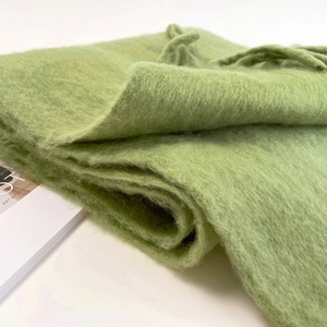 Close-up of green mohair scarf featuring fuzzy texture and soft fringe detail