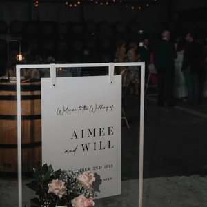 White wedding welcome sign with black lettering on metal stand at evening reception