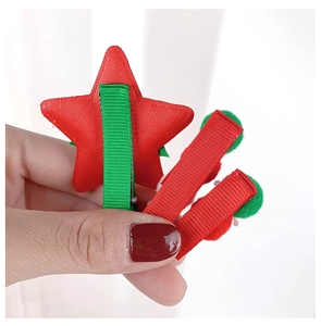Detail of Christmas star hair clips with red ribbon and green pom-pom accents
