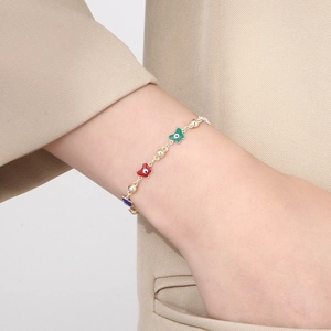 Modisches goldenes Kupferarmband mit bunten Schmetterlings- und Evil-Eye-Anhängern am Handgelenk