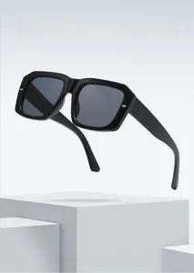 Detail of square black sunglasses with metal accents on a modern white pedestal display