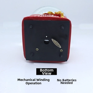 Close-up of the red musical snow globe base with mechanical wind-up key and screw details