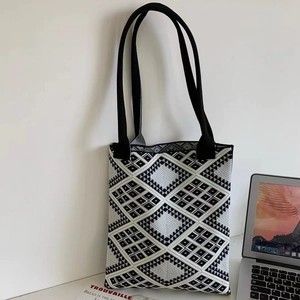 Close-up of geometric knit tote bag with thick texture leaning against a white wall