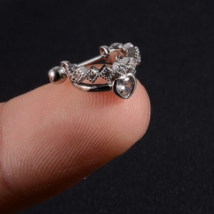 Close-up of heart-shaped zircon crown cartilage stud earring held on a fingertip