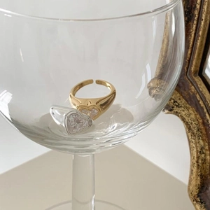 Creative display of gold and silver adjustable rings with heart zircon in a glass