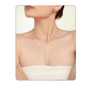 Macro detail of a 18K gold-plated double-layer necklace with a rectangular zircon pendant