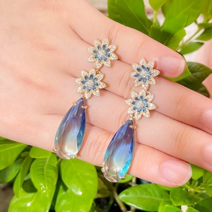 Golden flower earrings with gradient blue water drop sapphire crystals held by hand