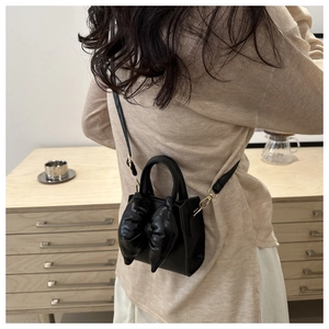 Detailed back view of a chic black crossbody bag with a large bow showing on-body fit