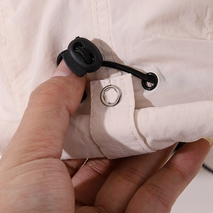 Detail of adjustable drawstring toggle and metal eyelet on children's sun hat fabric