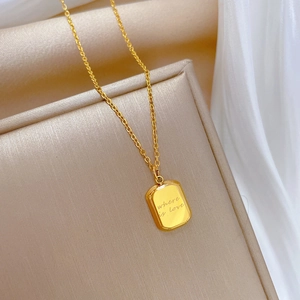 Macro detail of gold-plated rectangular pendant with 'where is love' engraving