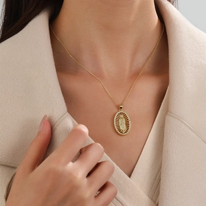 Detailed view of a gold-plated Virgin Mary pendant necklace with zircon crystals on a model