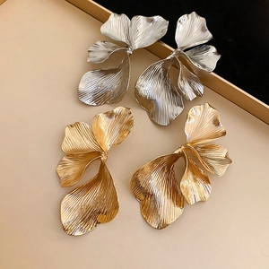 Close-up of gold and silver textured 3D flower stud earrings on a jewelry tray