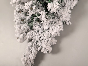 Macro shot of artificial snow-flocked pine needles on a green Christmas decorative branch