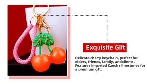 Detail of red cherry keychain with green rhinestone leaf and pink woven strap