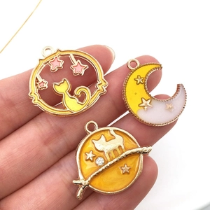Macro shot of gold alloy moon and cat charms for DIY jewelry making on white background