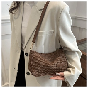 Detail of vintage brown shoulder bag featuring woven texture and leather logo tag