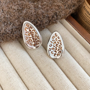 Detailed close-up of leaf-shaped leopard print earrings placed in a beige jewelry box